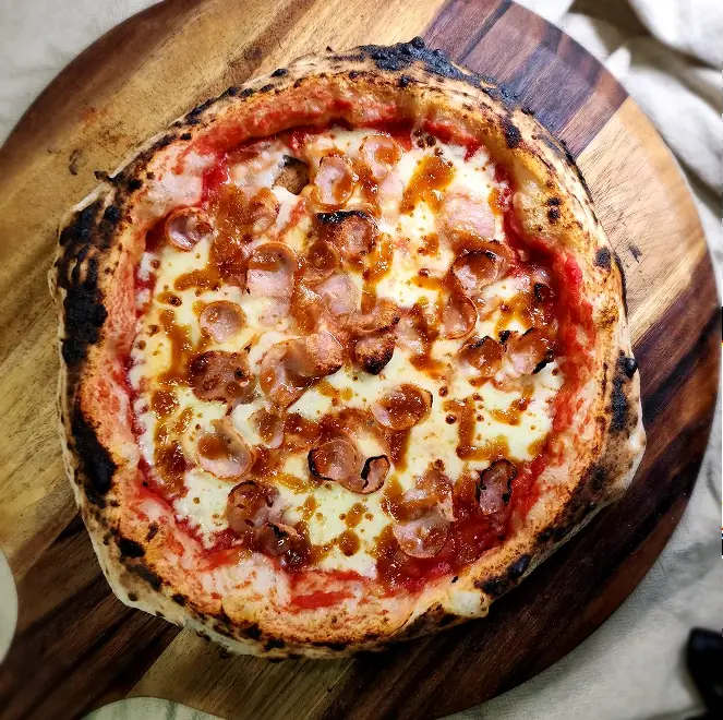 SR Pizza stone-fired pizza with red onion, olives, and mozzarella served in a takeaway box